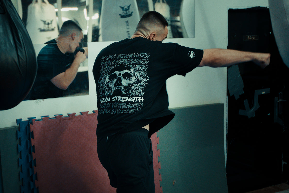 Boxtraining am Sandsack im schwarzen Azan Strength T-Shirt mit Totenkopf-Rückenprint